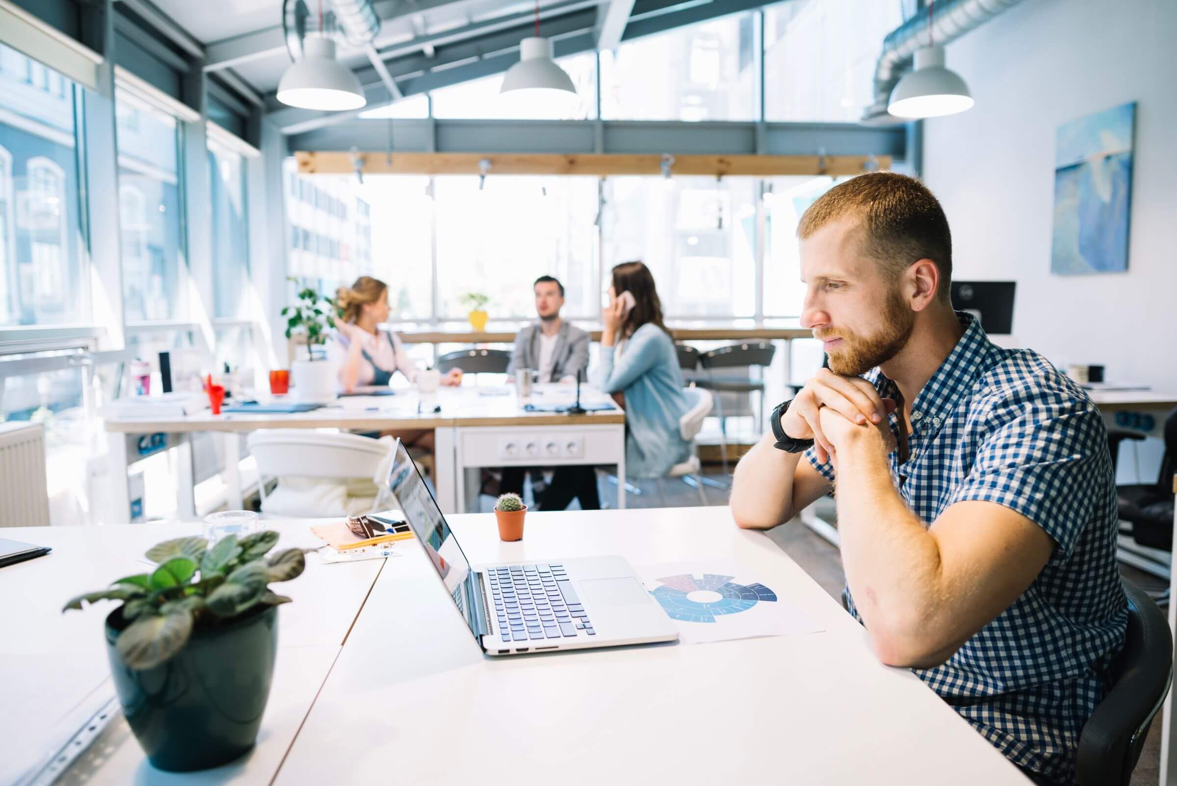 Office environment with focused team members working individually and collaborating in the background, representing asynchronous work culture.